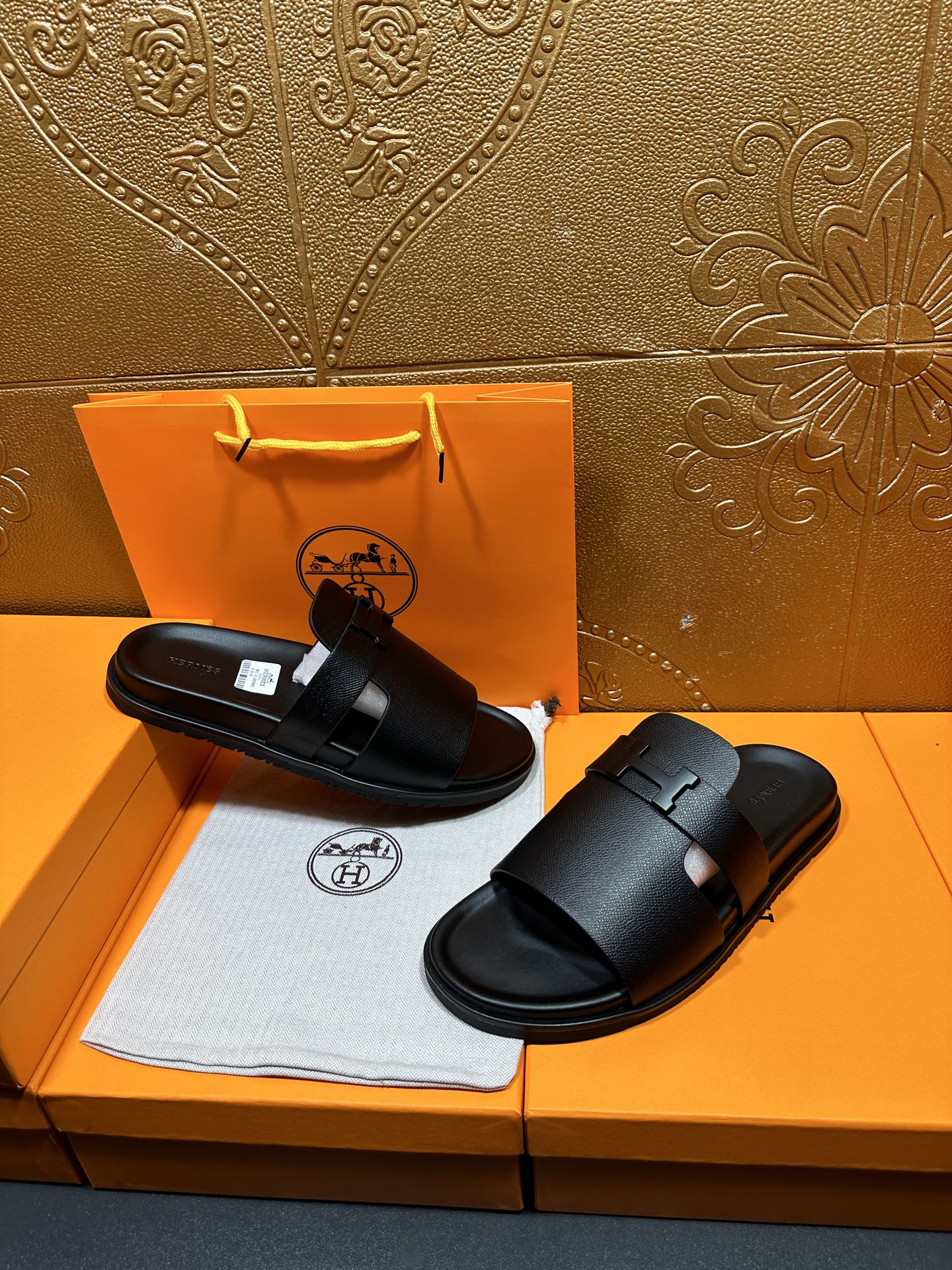 Black leather slide sandals with double strap design and wide buckle closure.