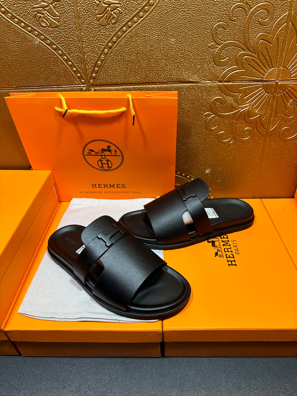 Black leather slide sandals with front buckle strap and contoured sole edge.