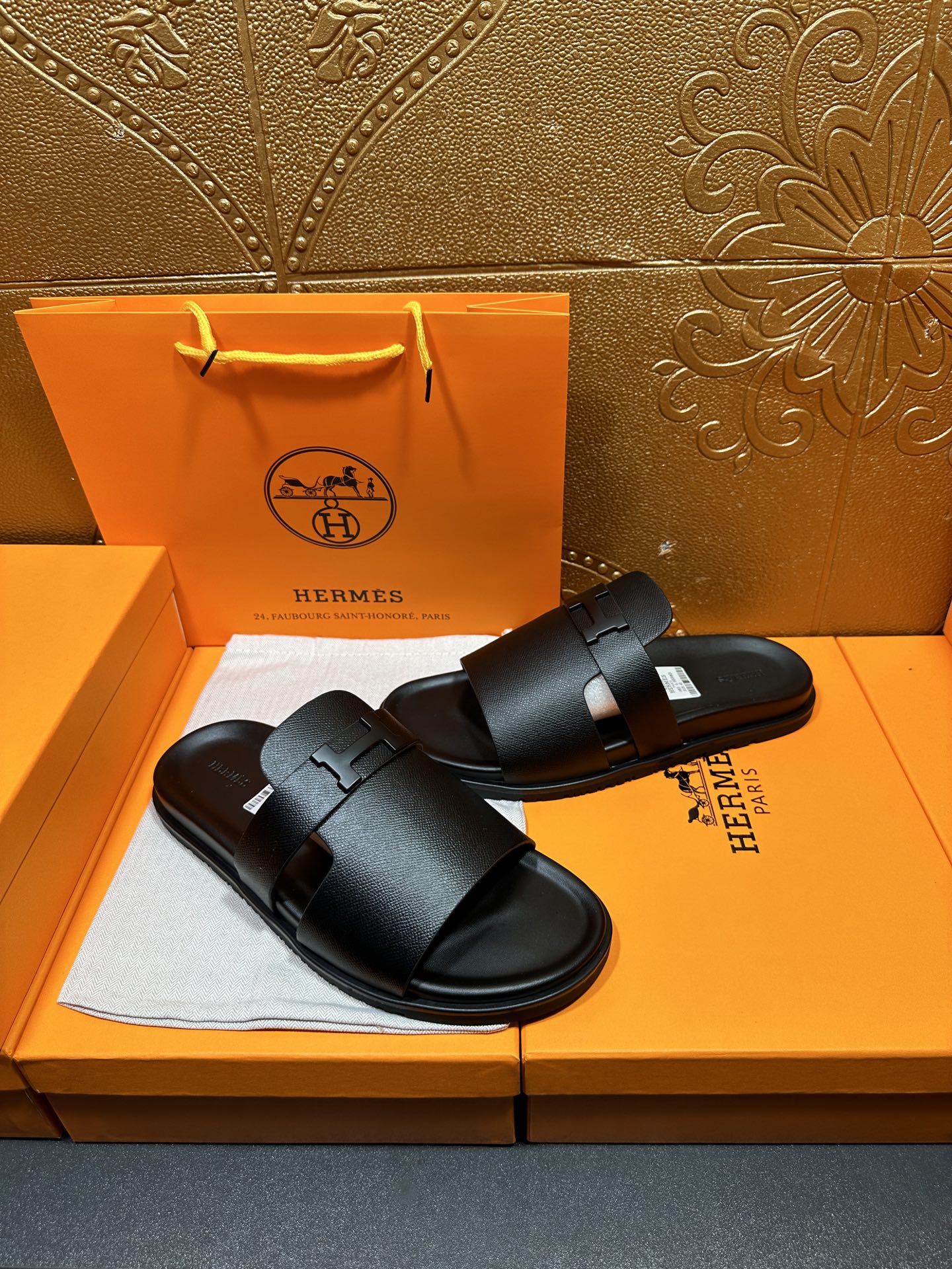 Black leather slide sandals with front buckle strap and contoured sole edge.