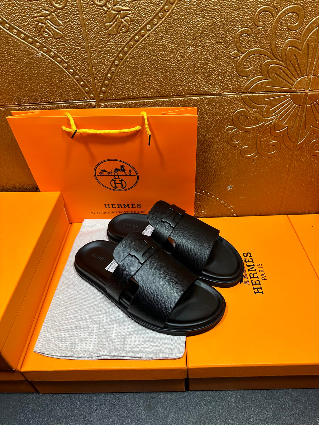 Black leather slide sandals with curved footbed and front buckle strap detail.