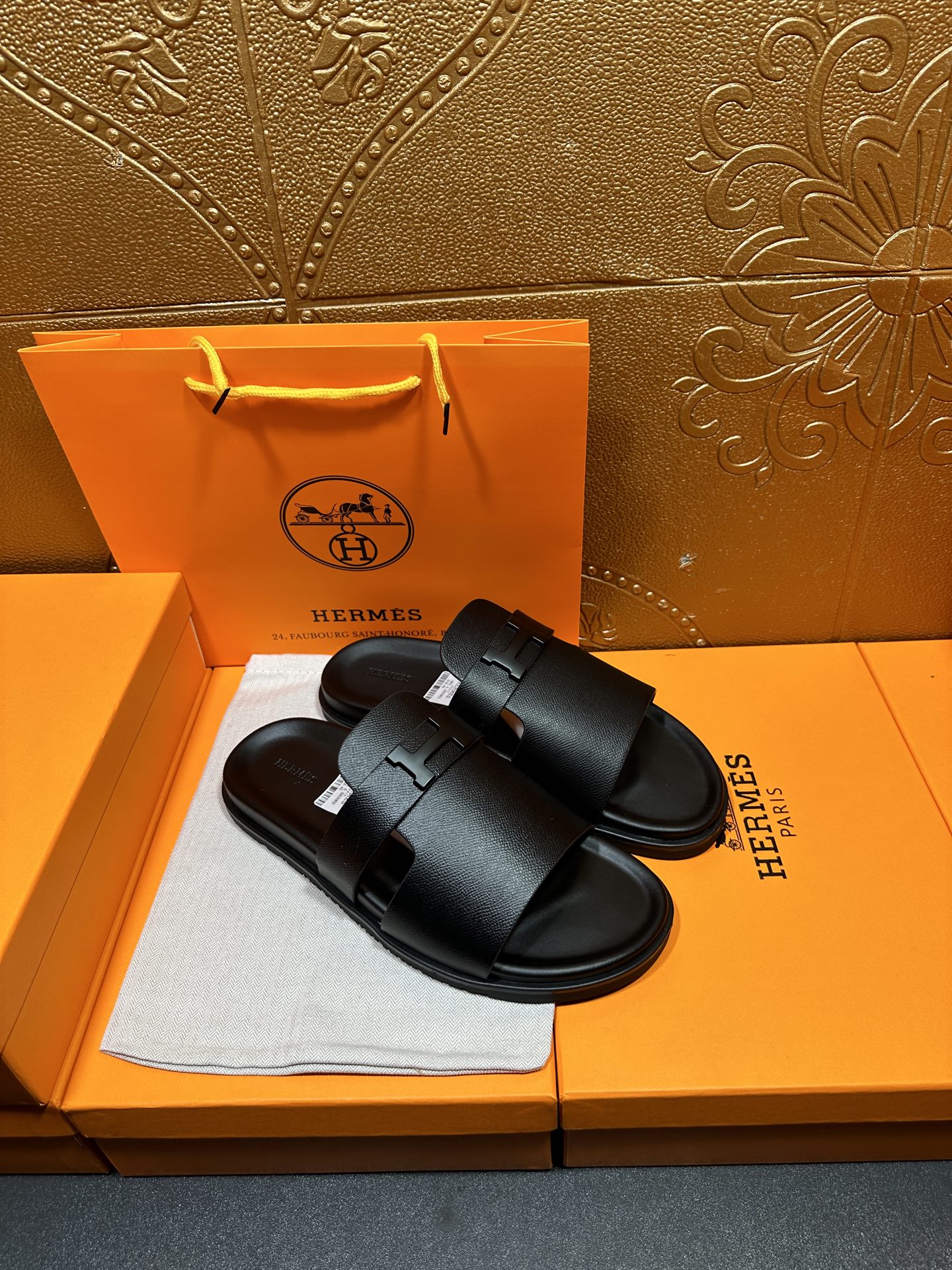 Black leather slide sandals with curved footbed and front buckle strap detail.