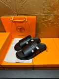 Black leather slide sandals with adjustable buckle strap, open-toe style.