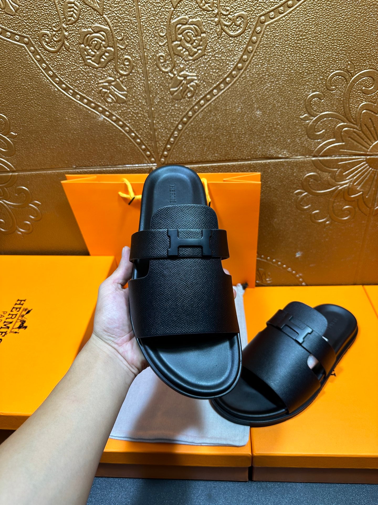 Close-up of black leather slide sandal with textured strap and buckle detail.