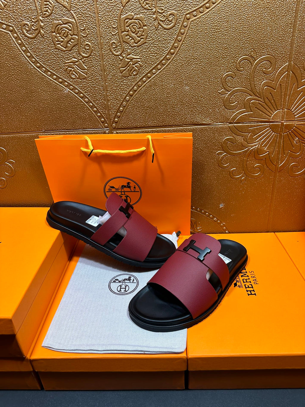 Hermes slide sandals with burgundy straps, silver H buckle, black footbed, pair shown.