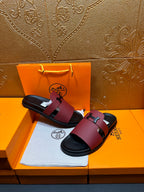 Hermes slide sandals with burgundy straps, silver H buckle, black footbed, pair shown.