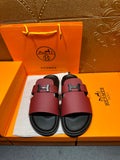 Hermes slide sandals with burgundy leather straps and silver H buckle, black footbed.