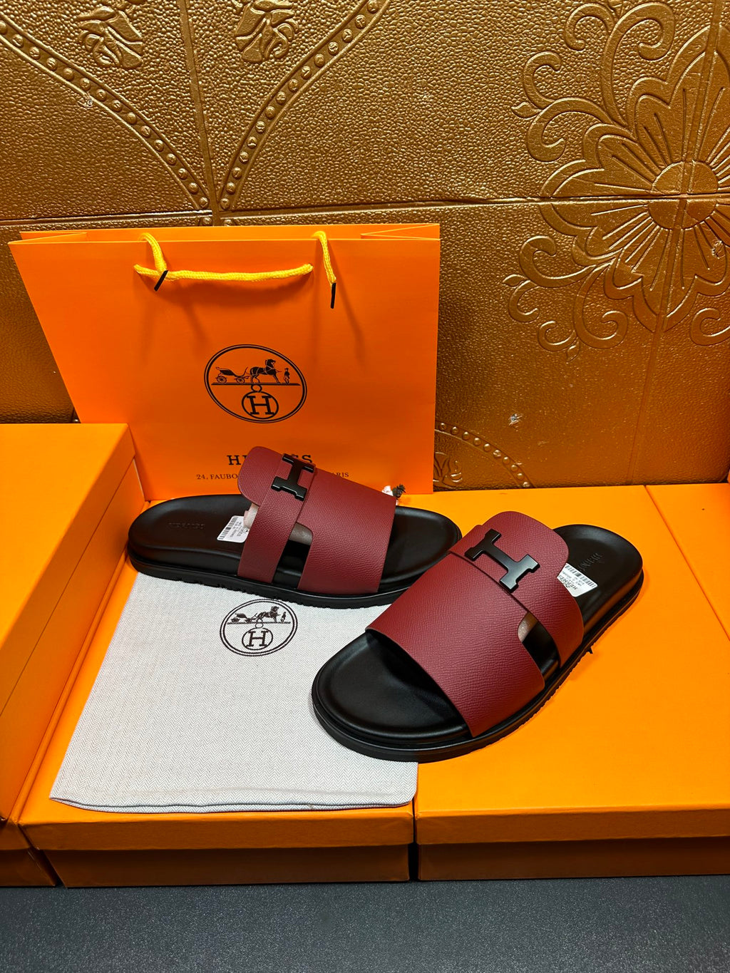 Hermes slide sandals with burgundy leather straps and silver H buckle, black soles.