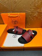 Hermes slide sandals with burgundy leather straps and silver H buckle, black soles.