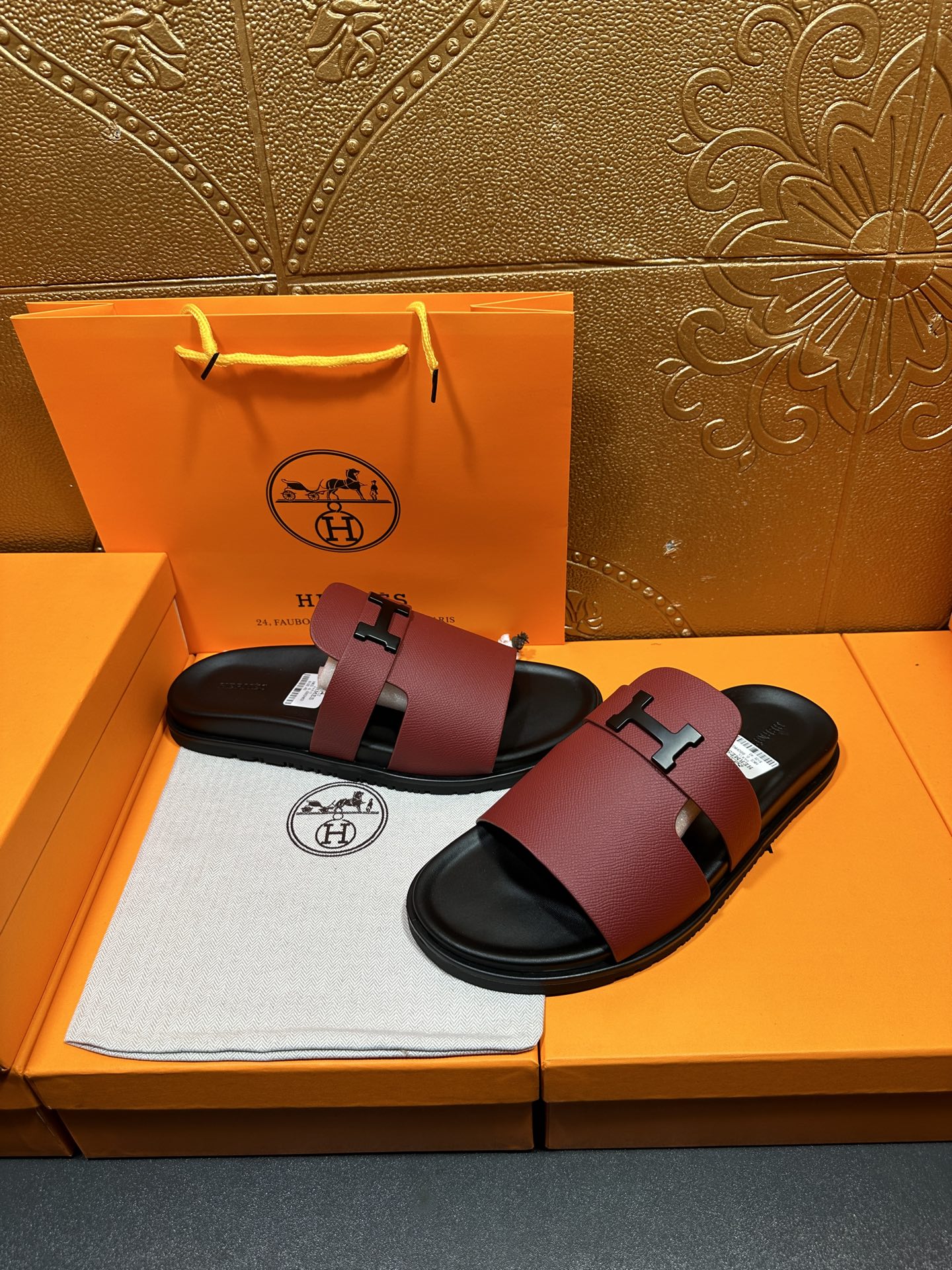 Hermes slide sandals with burgundy leather straps and silver H buckle, black soles.