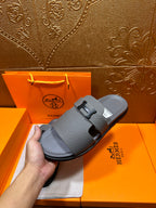 Dark gray slide sandals on display, square H buckle over instep