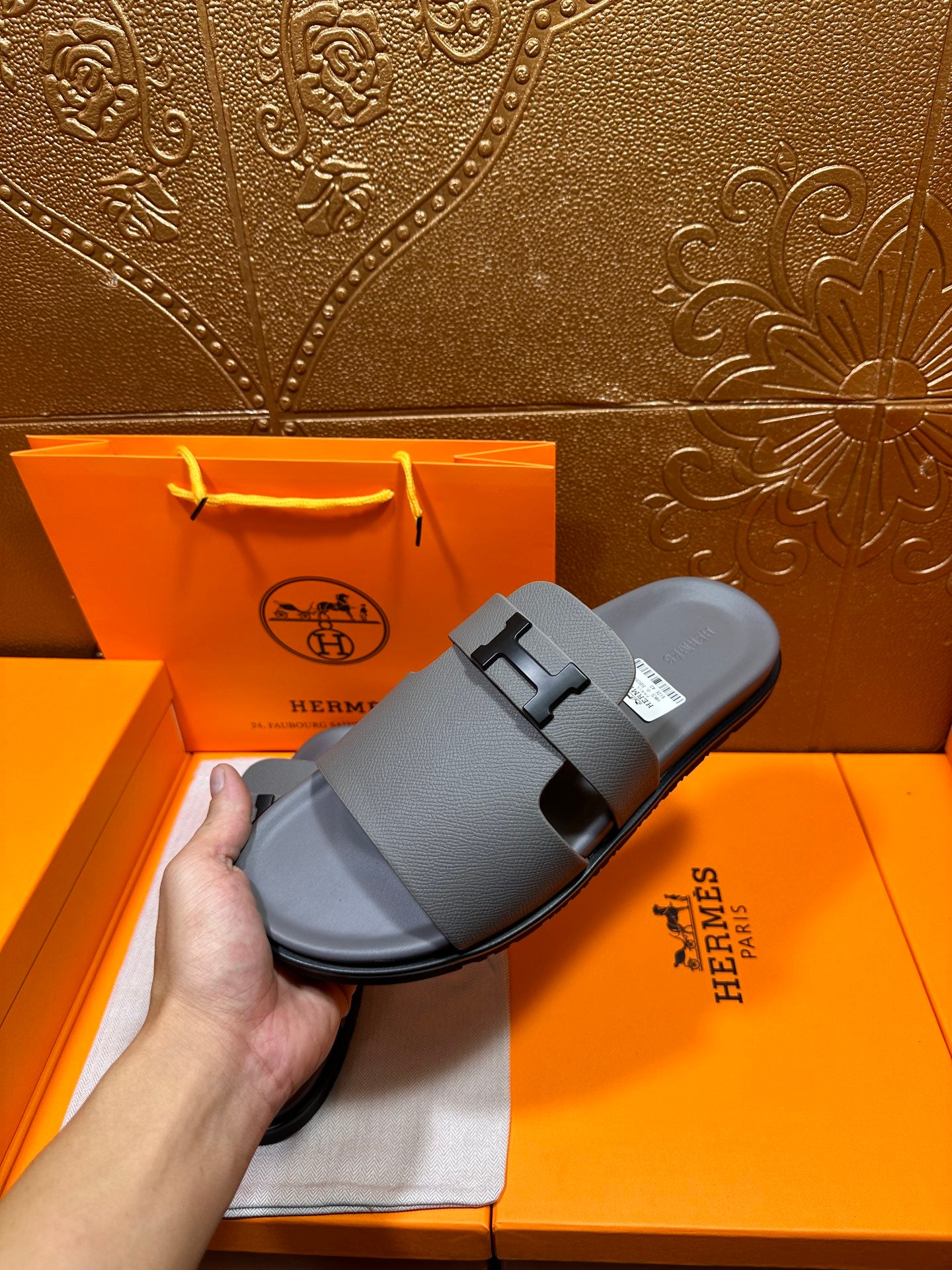 Dark gray slide sandals on display, square H buckle over instep