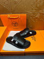 Hermes black textured slide sandals with wide band strap and flat rubber sole