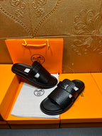 Hermes black textured slide sandals with wide crisscross straps and flat rubber base