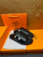 Hermes black textured slide sandals showing top strap detail and curved footbed