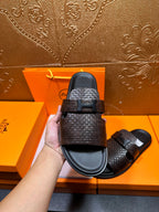 Hermes textured slide sandal close-up, dark brown strap with black buckle bar