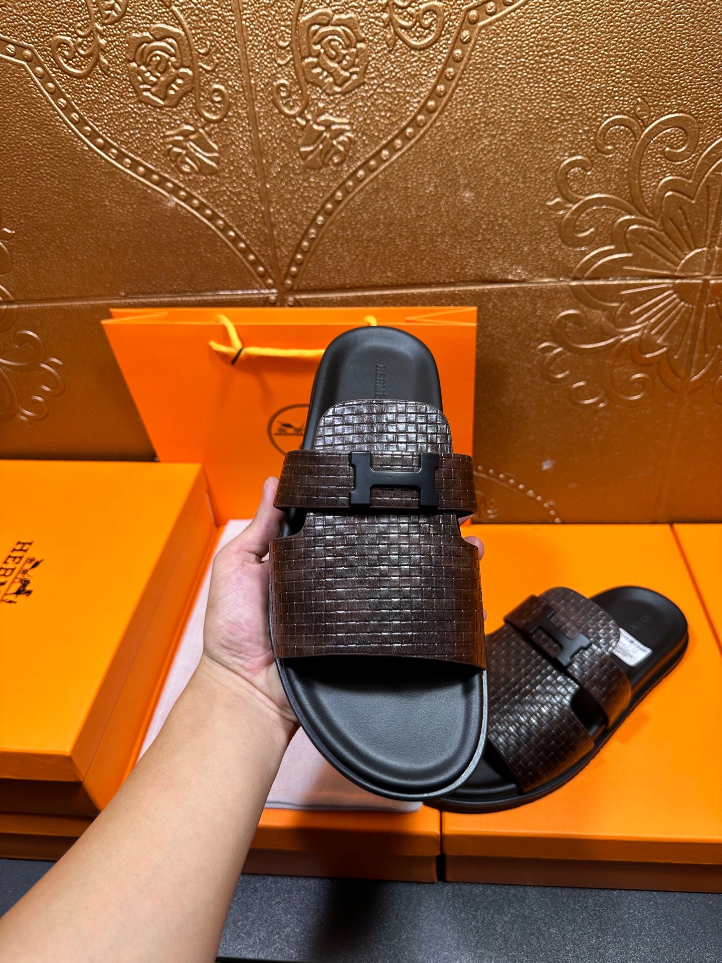 Hermes textured slide sandal close-up, dark brown strap with black buckle bar