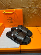 Hermes textured slide sandals laid flat, dark brown top strap with black buckle