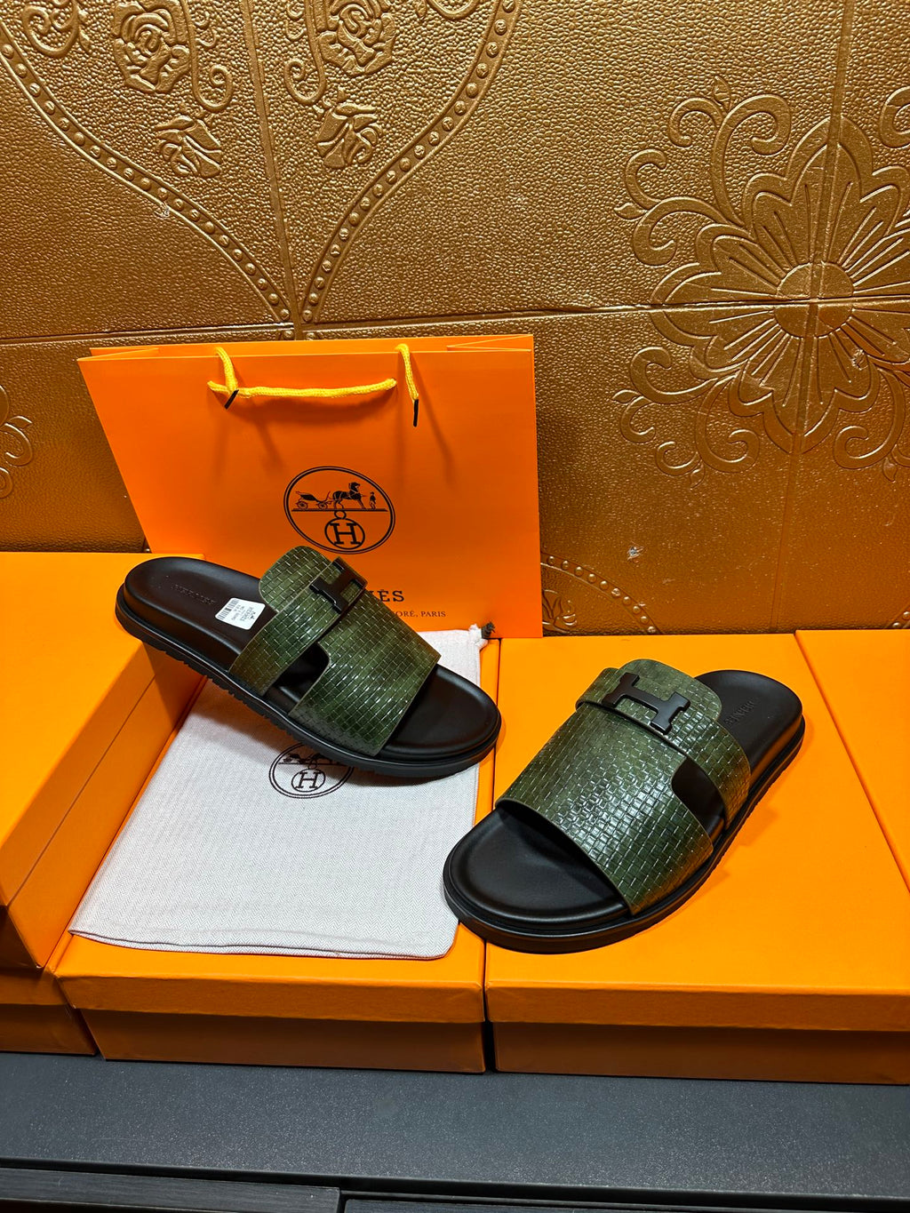 Hermes slide sandals with green textured straps and black rubber soles, displayed pair