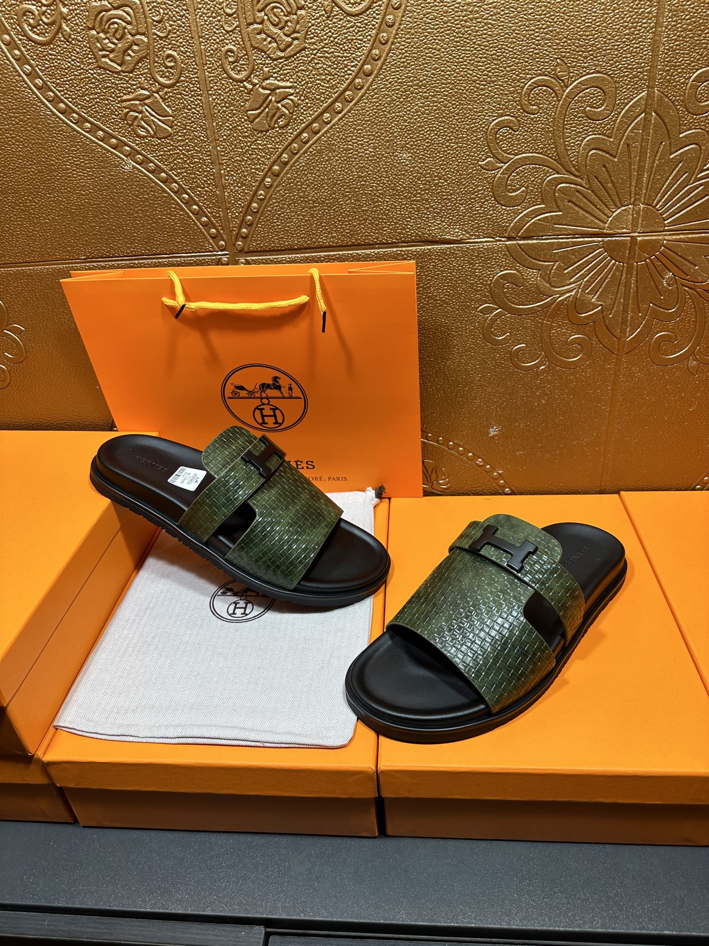 Hermes slide sandals with green textured straps and black rubber soles, displayed pair