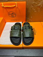 Hermes slide sandals with green textured straps and black rubber soles, two shoes