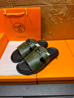Hermes slide sandals with green patterned straps, black footbed, angled pair view