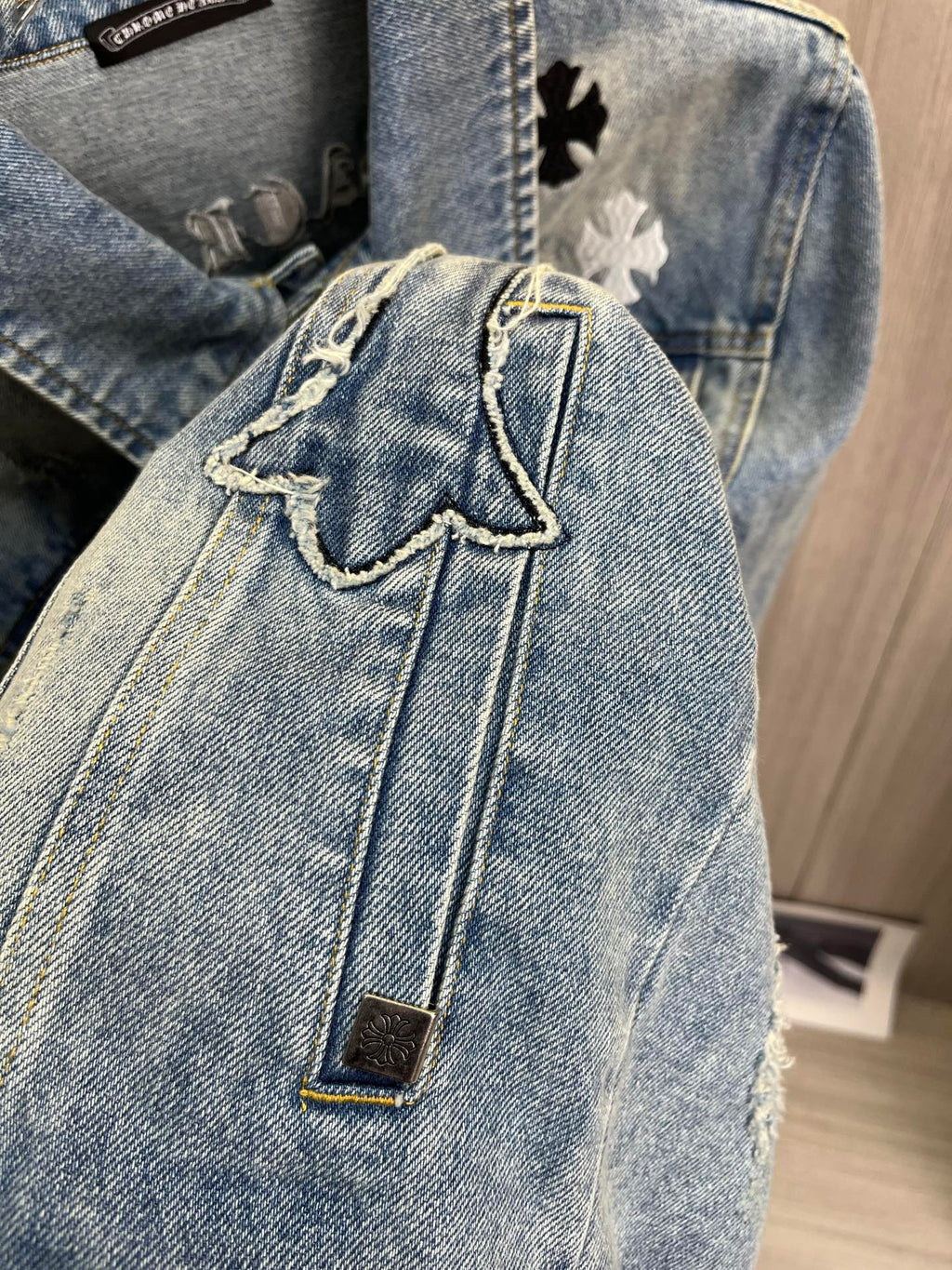 Light blue denim jacket close-up with stitched seams and gold metal button
