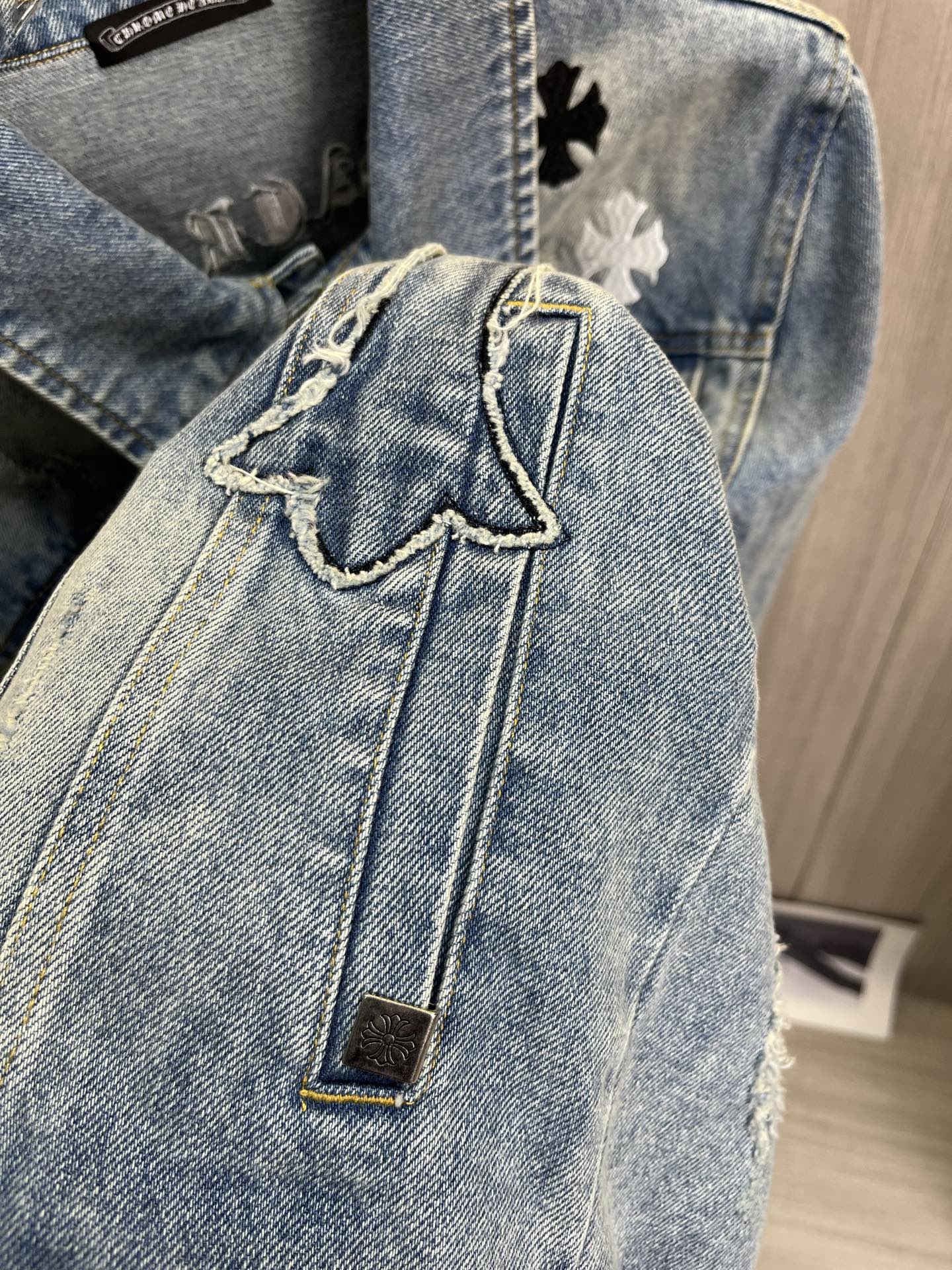 Light blue denim jacket close-up with stitched seams and gold metal button
