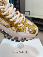 Versace chunky sneakers close-up, gold leather-look upper with white laces and logo trim