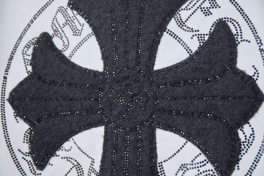 Close-up of black cross emblem with dotted trim on a white T-shirt