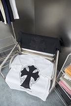 Folded white T-shirt on display rack with black cross emblem