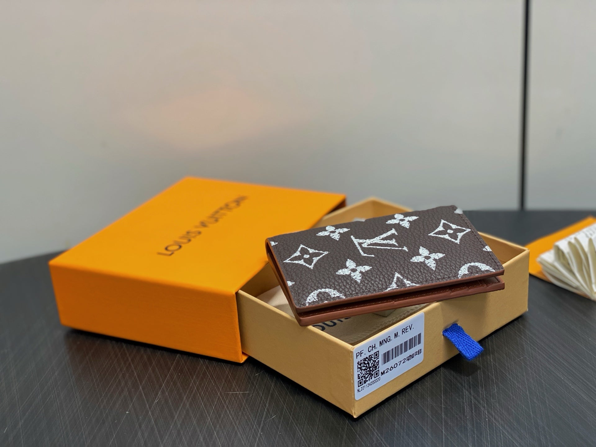 Monogram small wallet with dark brown and white pattern, resting in gift box