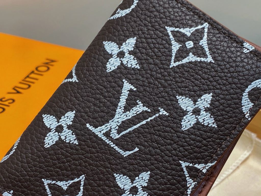 Dark brown textured leather small wallet with white monogram pattern close-up