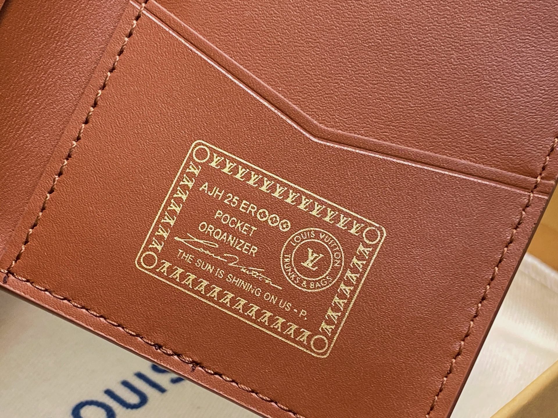 Brown leather wallet interior panel with embossed emblem and decorative text
