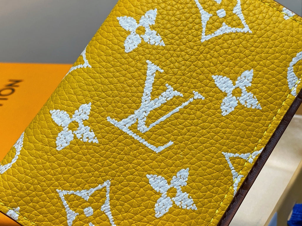 Small bag close-up: yellow textured surface with white floral monogram pattern