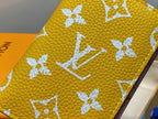 Small bag close-up: yellow textured surface with white floral monogram pattern