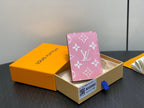 Pink monogram mini wallet standing in gift box with blue pull tab