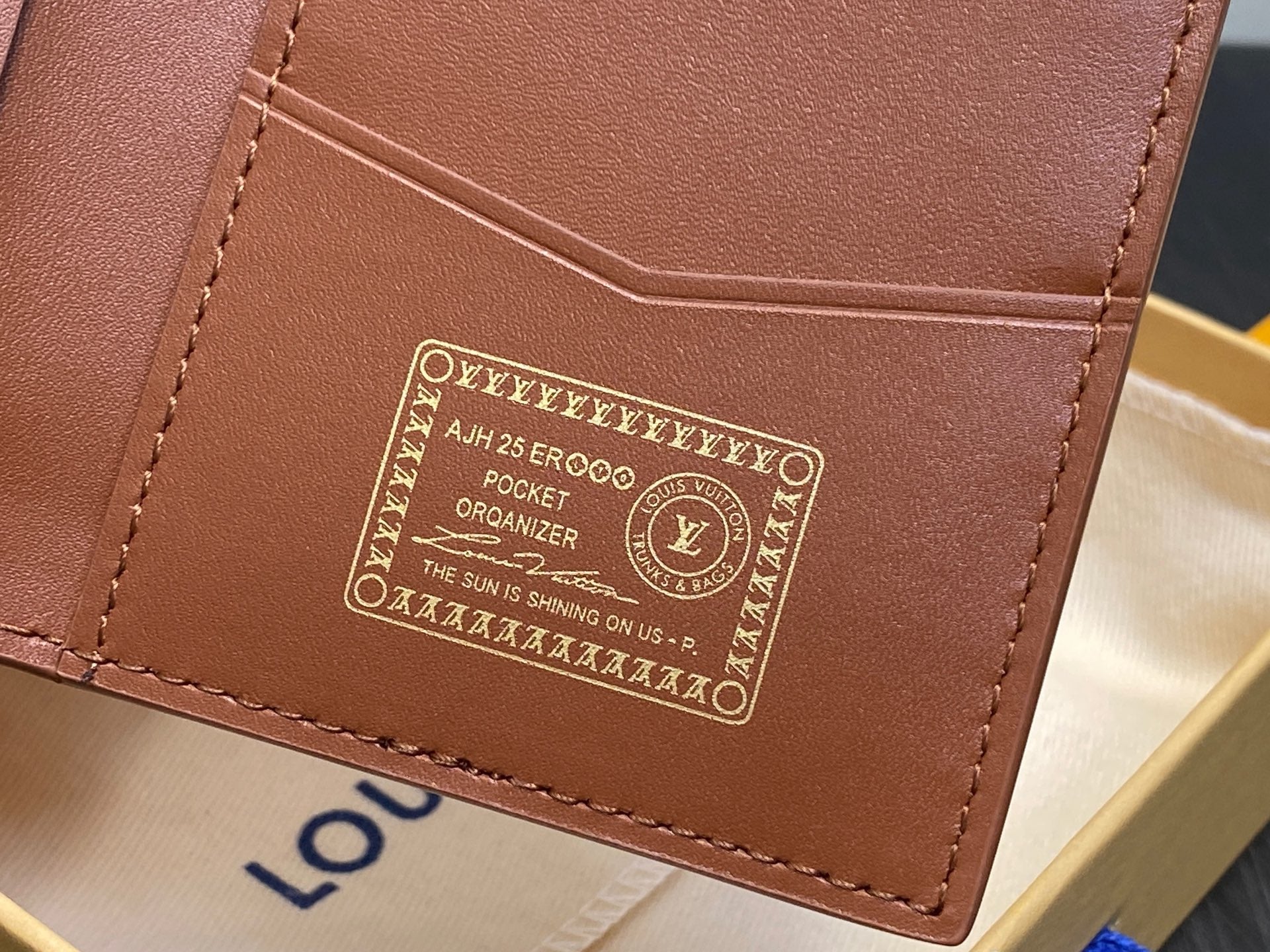 Brown mini wallet interior panel with gold printed label and stitching, close-up