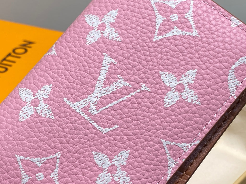 Pink textured mini wallet close-up with white monogram and flower motifs