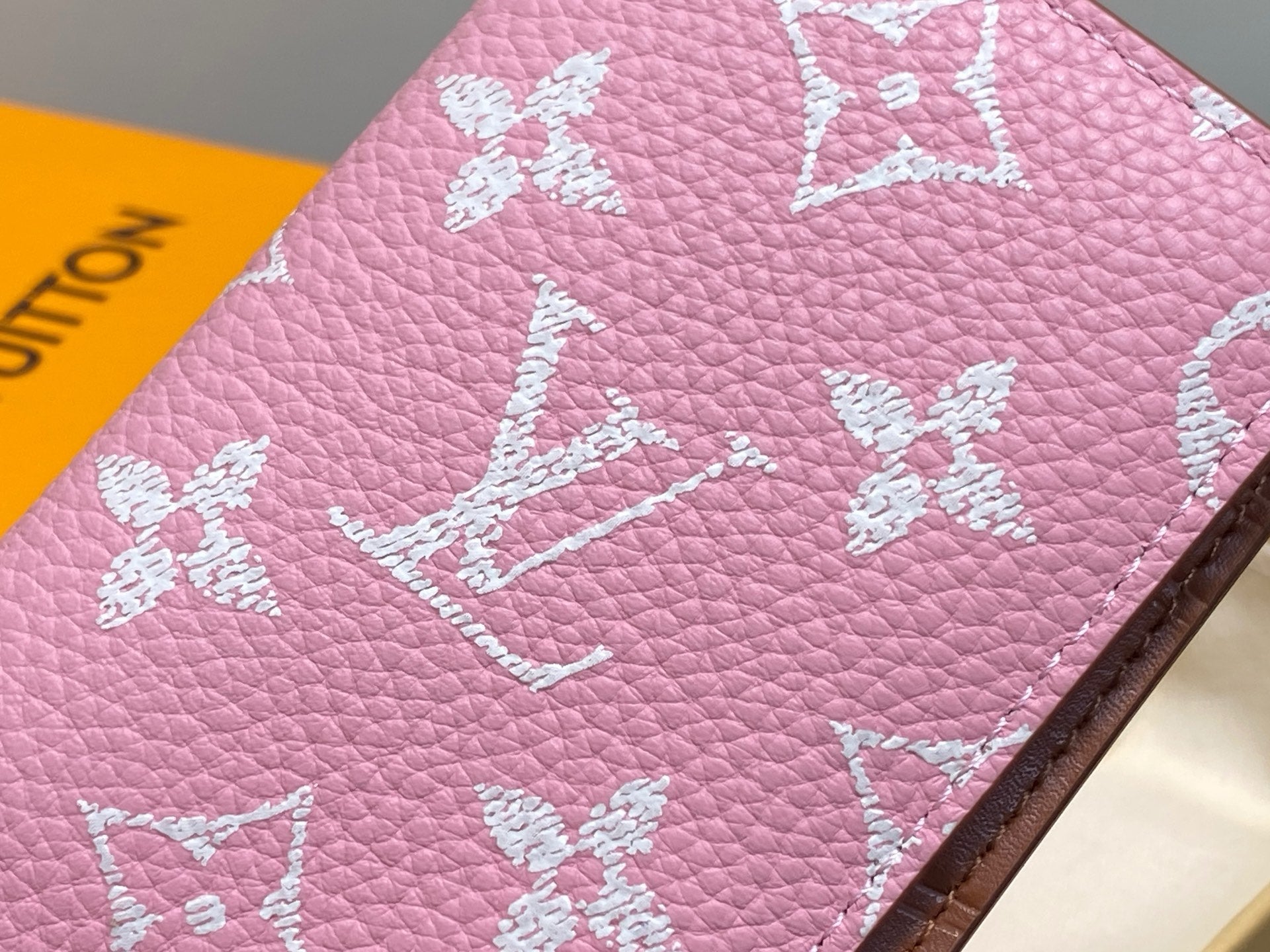 Pink textured mini wallet close-up with white monogram and flower motifs