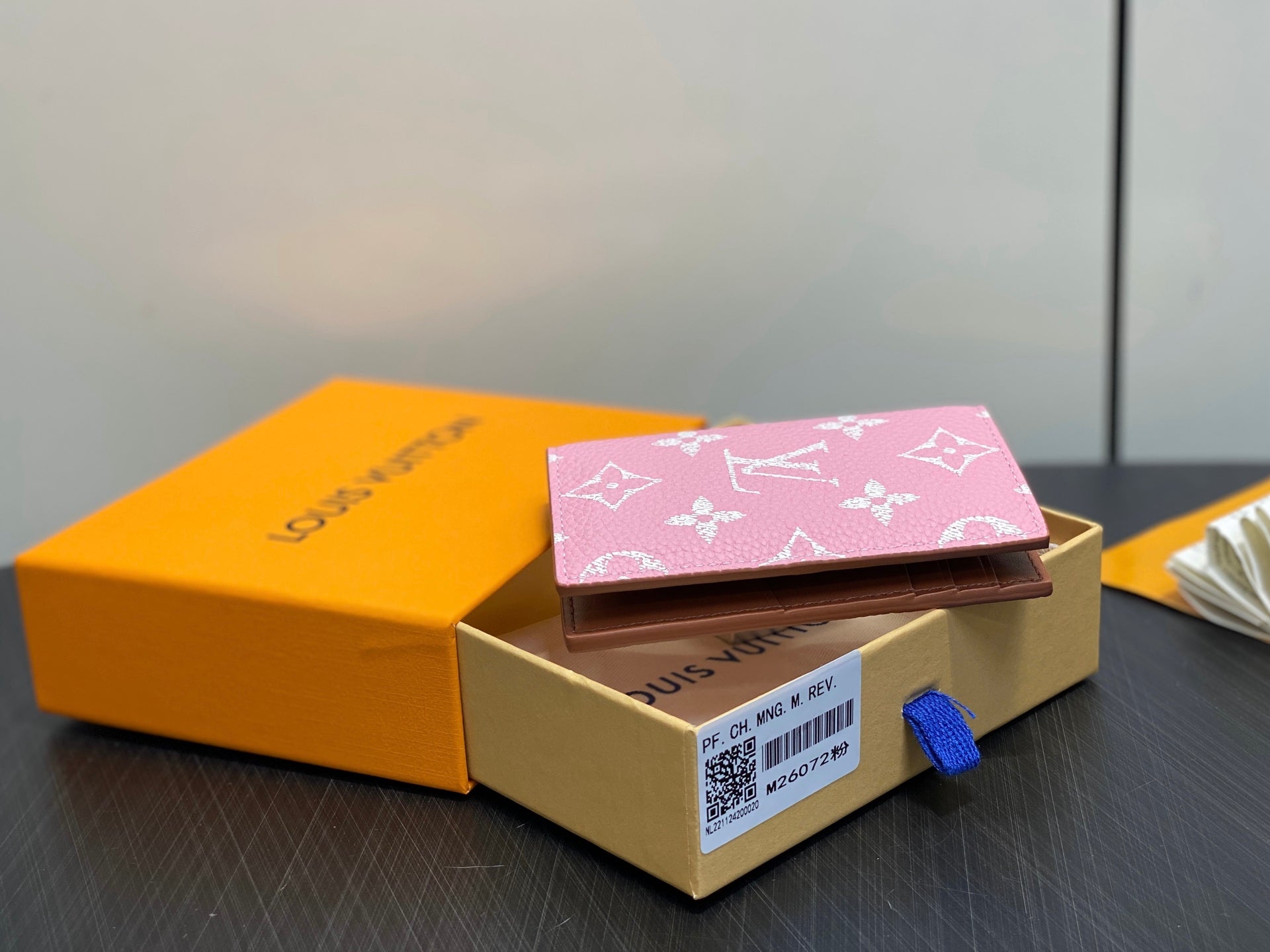 Pink monogram mini wallet closed in gift box with blue pull tab
