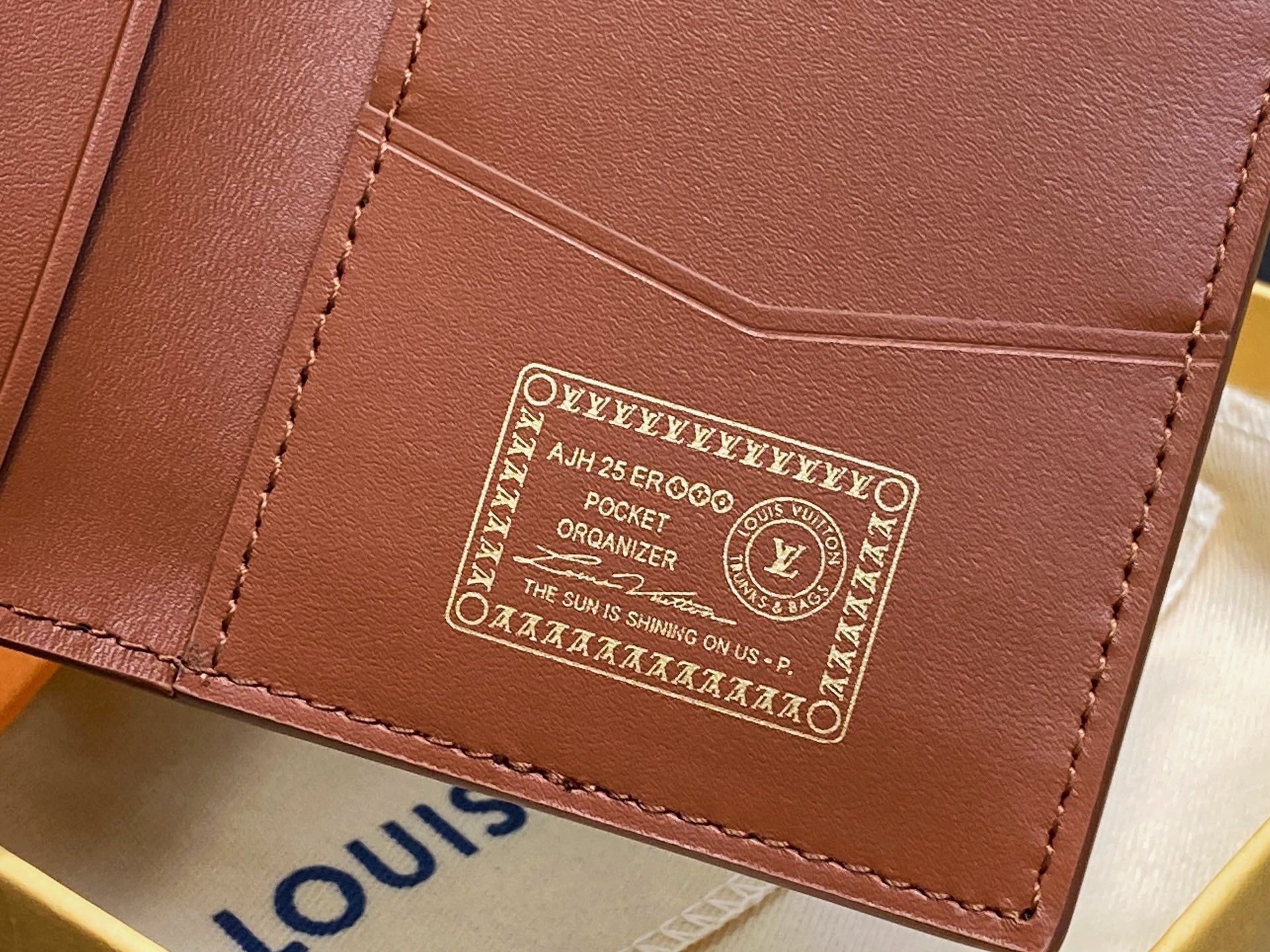 Small brown leather wallet with embossed logo patch and stitched edges