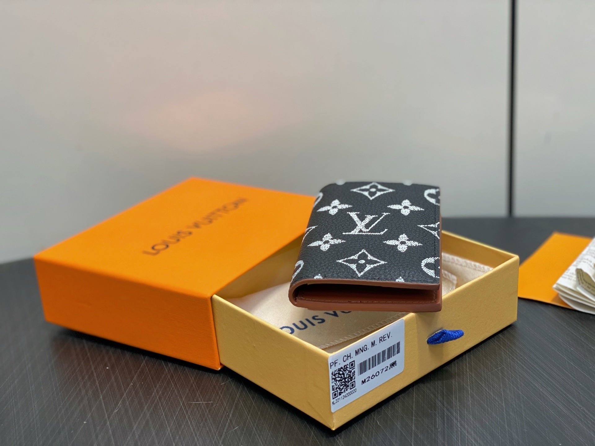 Small wallet with dark navy monogram exterior and beige interior, open