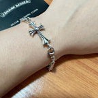 Silver-tone cross charm bracelet on wrist with chain and ring clasp