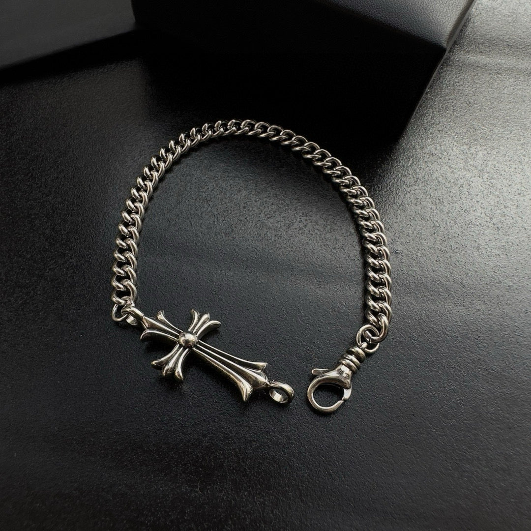 Silver-tone chain bracelet featuring a cross charm and ring clasp