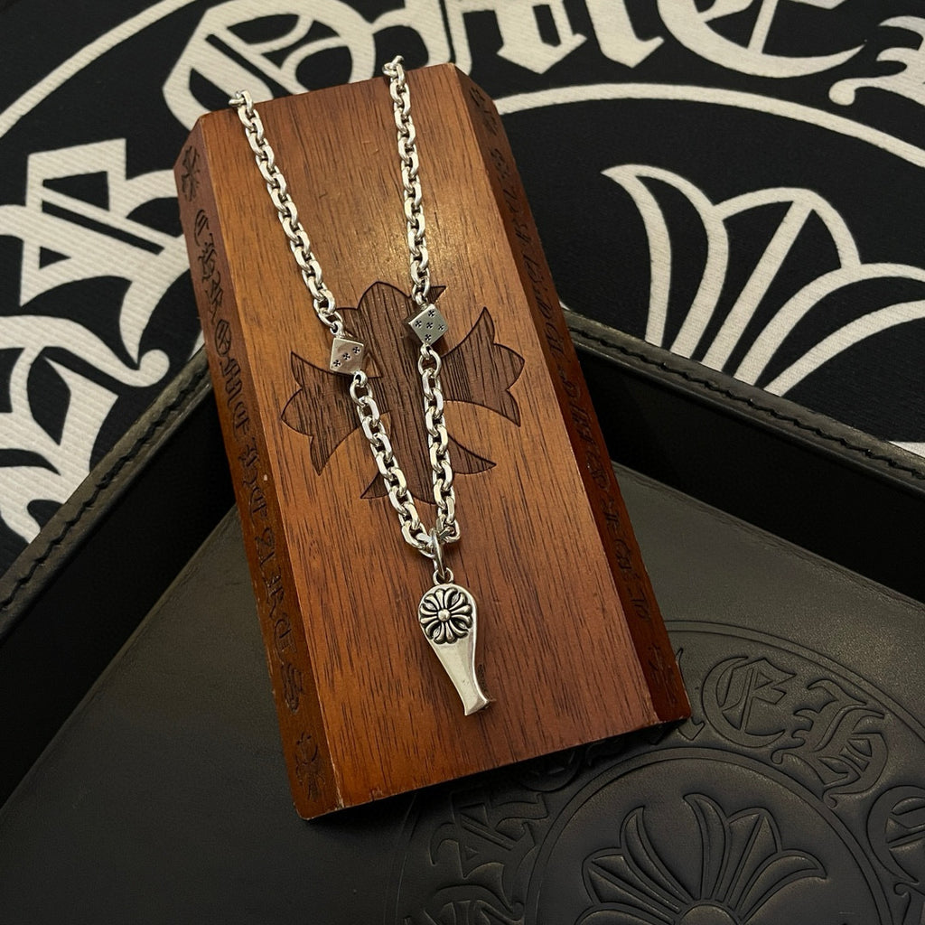 Silver-tone chain necklace with fleur de lis pendant and dagger charm on wooden card