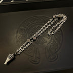 Silver-tone necklace chain on black leather jewelry box with floral emblem embossing