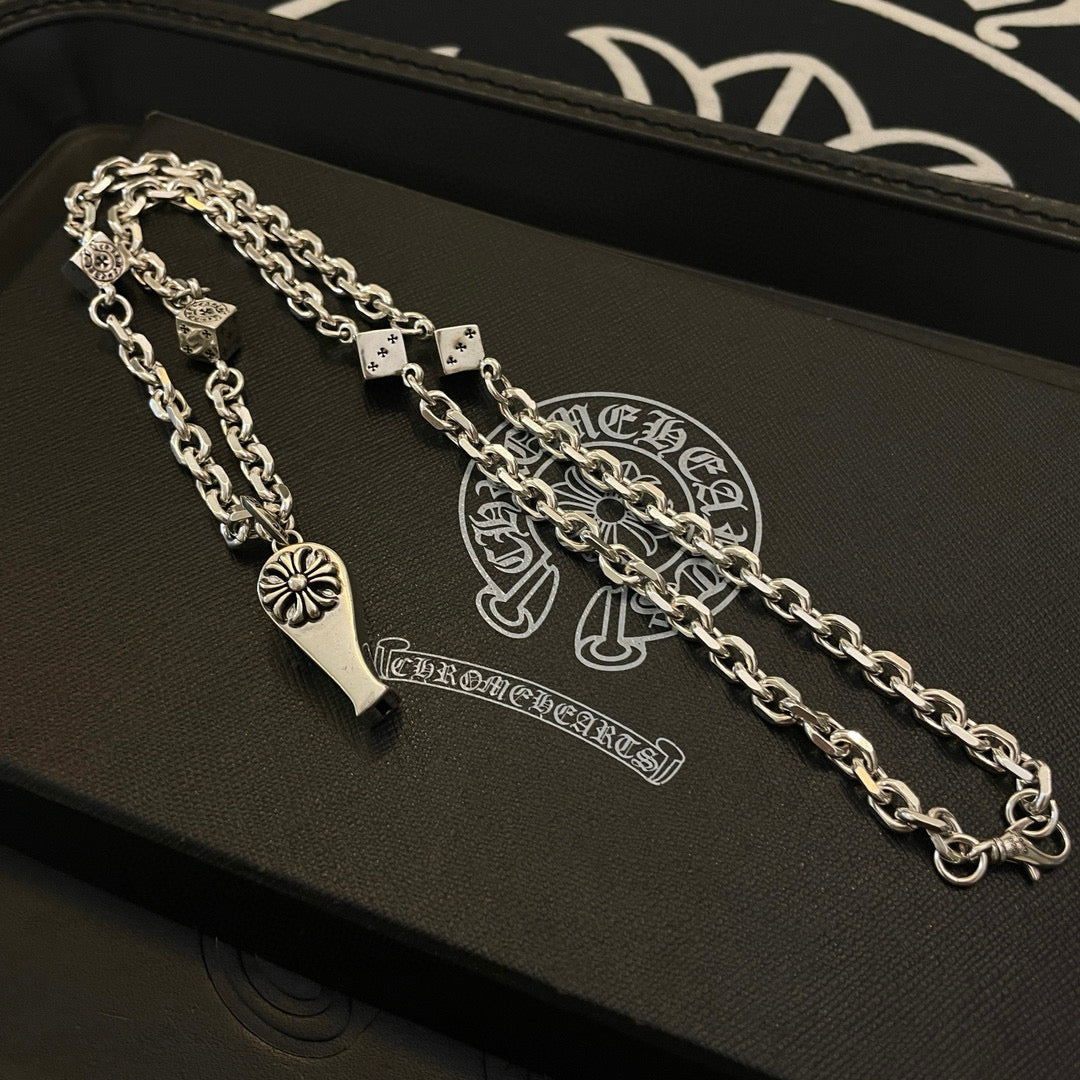 Silver-tone chain necklace with fleur de lis pendant and dagger charm on jewelry box