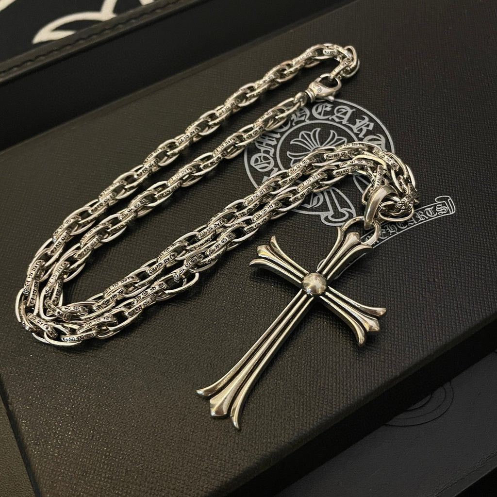 Silver-tone cross pendant necklace with stacked links, shown close-up