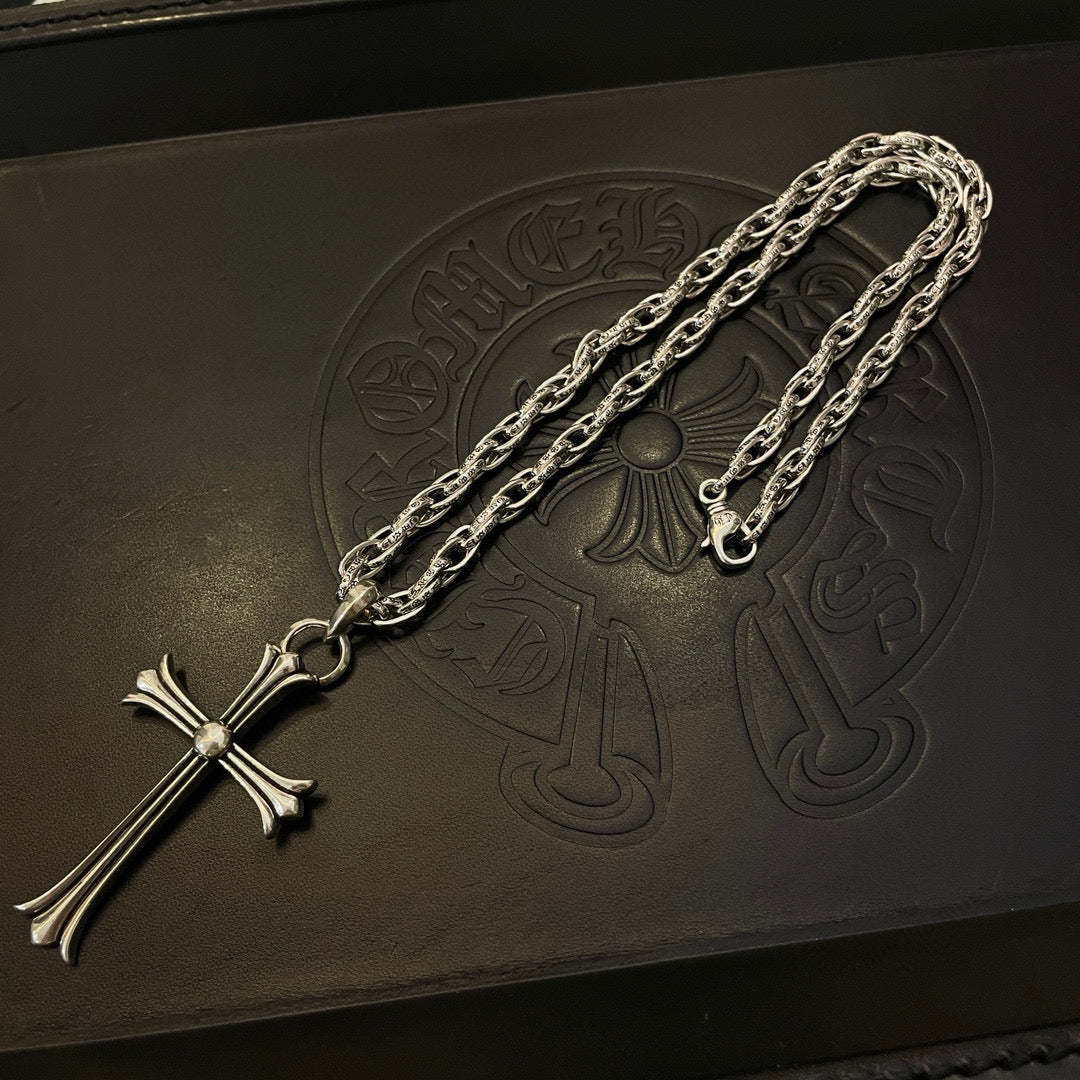 Silver-tone cross pendant necklace with long chain, laid flat