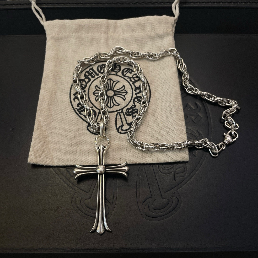 Silver-tone cross pendant necklace on fabric pouch with chain links